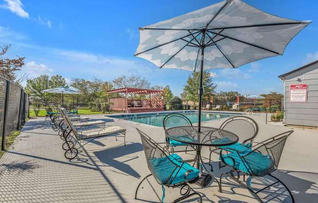 A patio with a table and chairs under an umbrella.