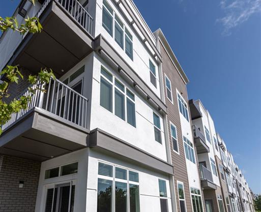 a white and brown apartment building with a lawn
