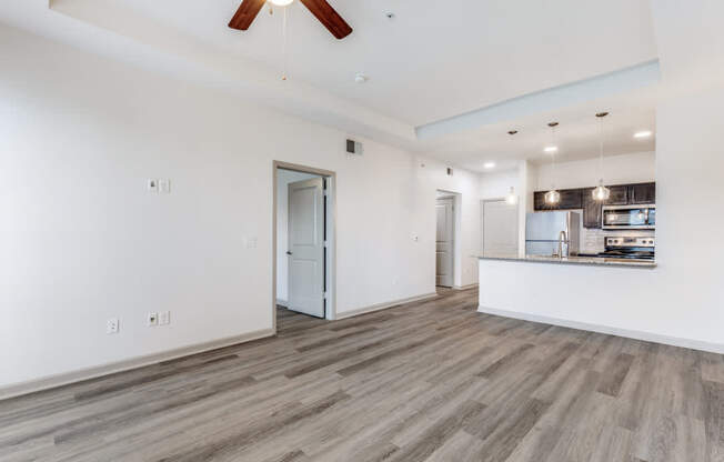 A spacious room with a ceiling fan and wooden flooring.