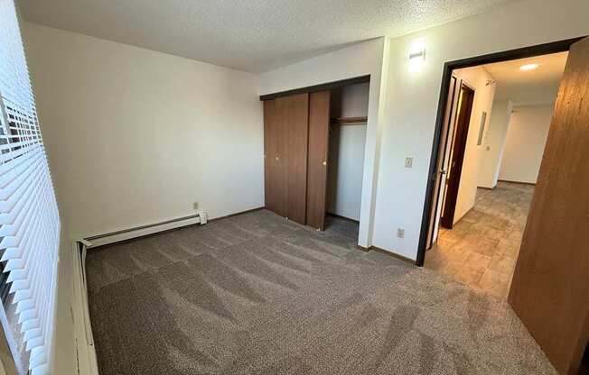A room with carpeted floor and a window with blinds.