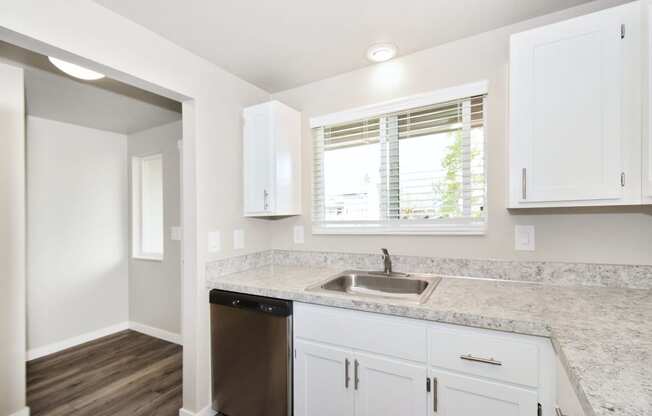 a kitchen with white cabinets and a sink and a window