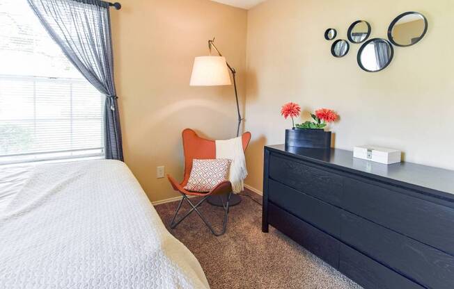 A bedroom with a bed, chair, and dresser.