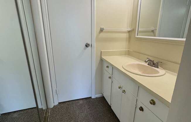 A bathroom with a sink, mirror, and cabinets.