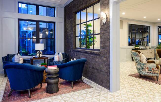 A living room with a blue chair and a table with a lamp on it.