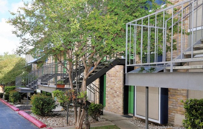 a building with a staircase and trees in front of it