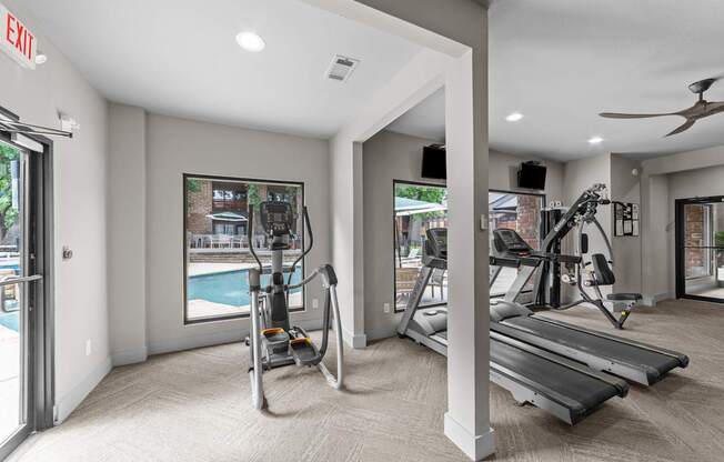 A gym with treadmills, elliptical machines, and a fan.