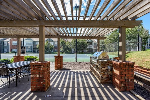 A tennis court is visible through a wooden pergola.