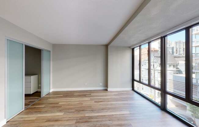 a bedroom with a large window and hardwood floors