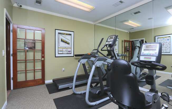 a gym with cardio equipment and mirrors on the wall