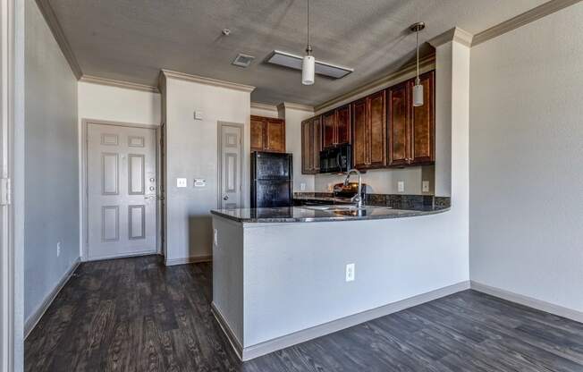 an empty living room with a kitchen in the background