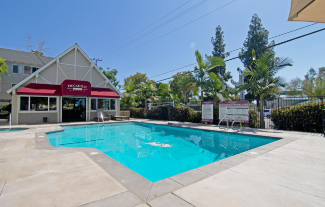 A pool in front of a building with a red awning.