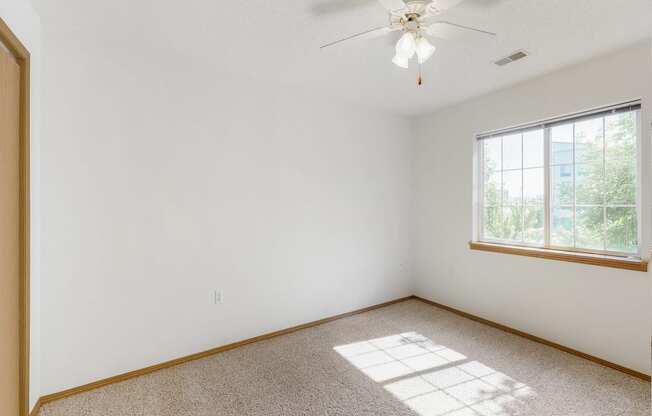 an empty room with a window and a ceiling fan