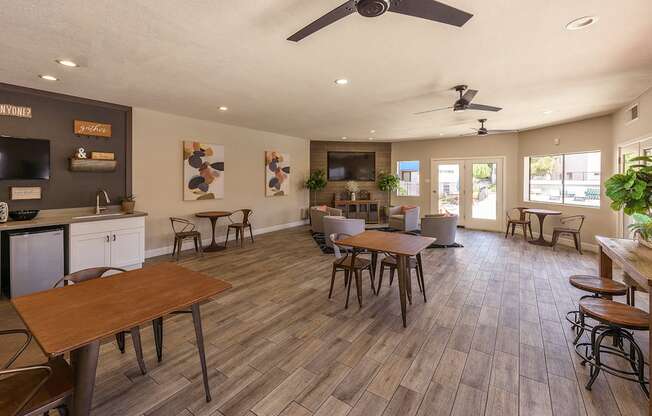 a community room with tables and chairs and a kitchen and a tv