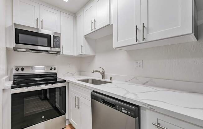 A modern kitchen with white cabinets and appliances.