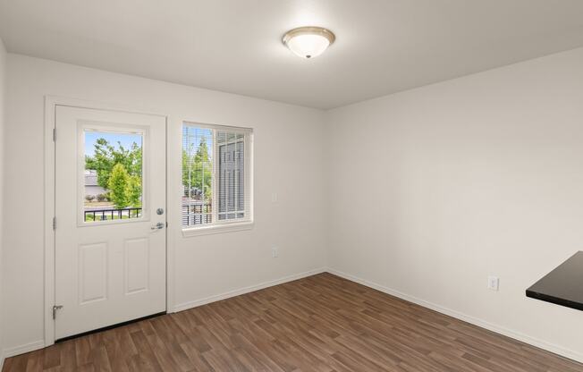 an empty living room with white walls and a door to a balcony