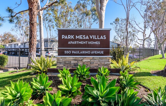 A sign for Park Mesa Villas Apartment Homes stands in front of a tree.