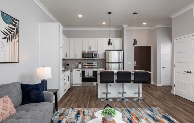 A modern kitchen with a grey sofa and a dining table with four chairs.