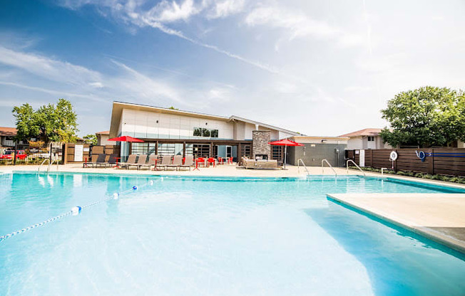 a large swimming pool with umbrellas and a building in the background