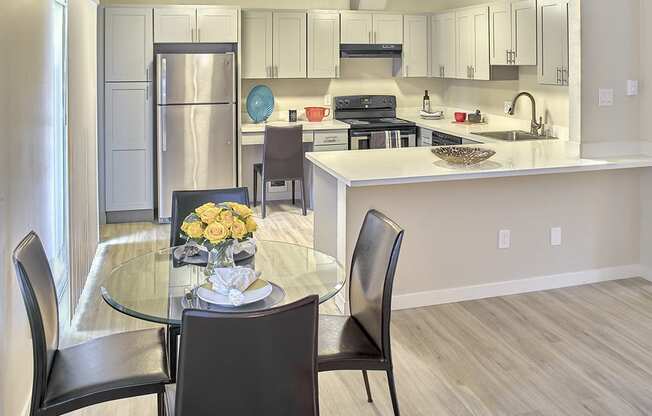 a kitchen with white cabinets and a white counter top and a glass table with black chairs  at 3030 Lake City, Seattle, WA