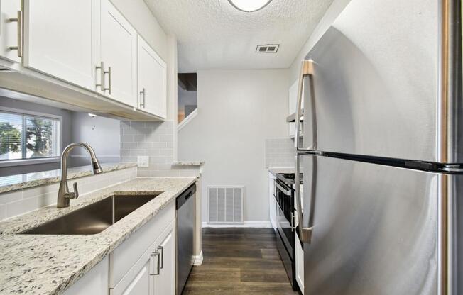 a kitchen with white cabinets and a stainless steel refrigerator