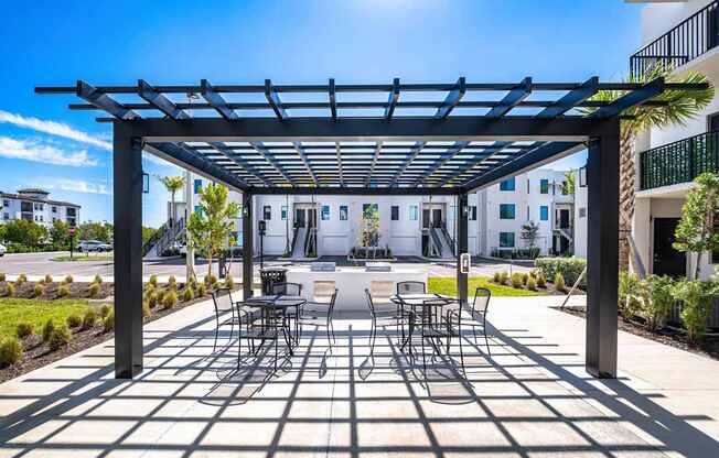 A patio with a table and chairs under a black pergola.