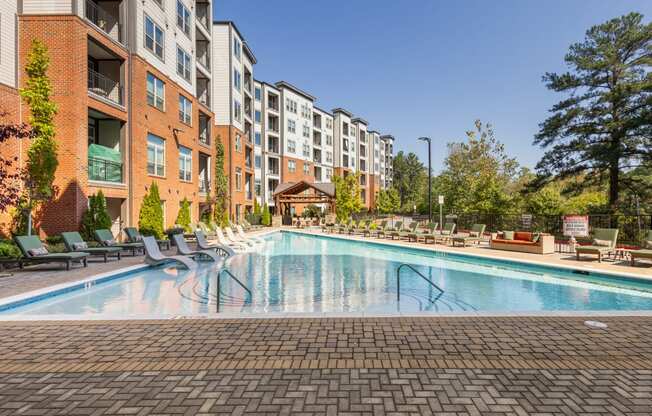 a swimming pool at an apartment building with a pool and lounge chairs