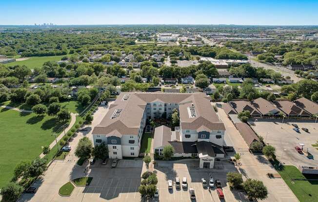 an aerial view of a large building in a neighborhood with cars on the street