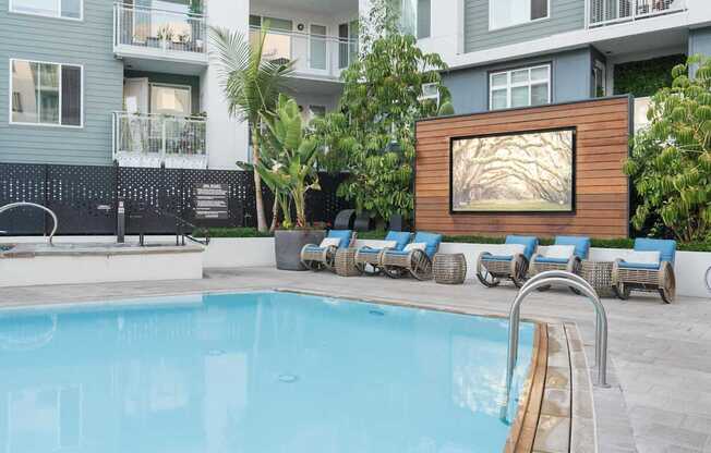 A pool with lounge chairs and a painting on a wall.