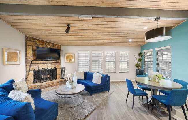 a living room with blue couches and chairs and a fireplace with a tv above it