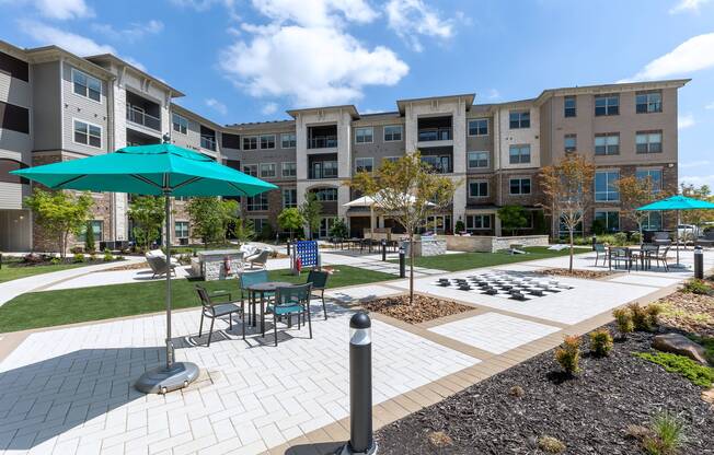 Outdoor game area with ample seating and umbrella at Cyan Craig Ranch apartments for rent in McKinney, TX