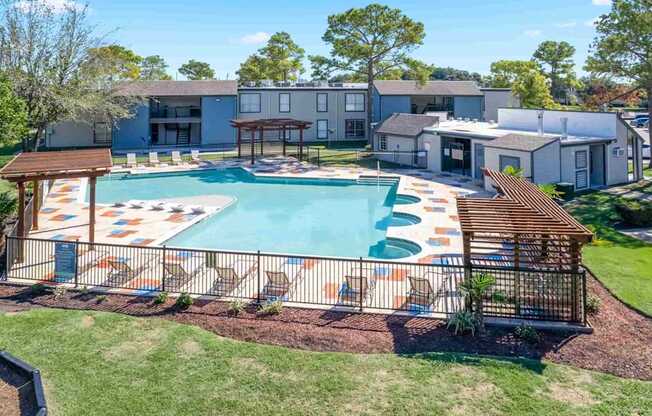 A swimming pool with a wooden deck and a building in the background.