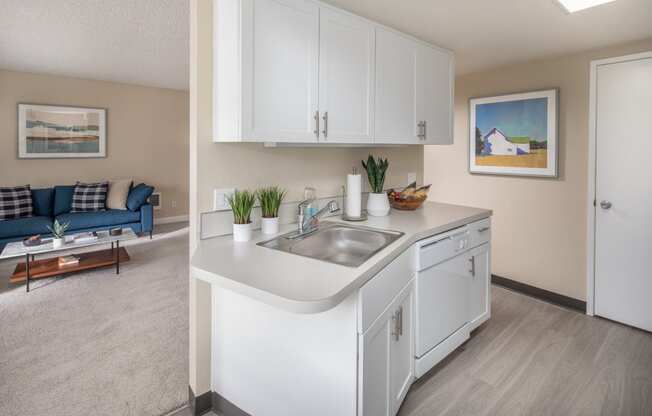 a kitchen with white cabinets and a sink and a living room with a couch