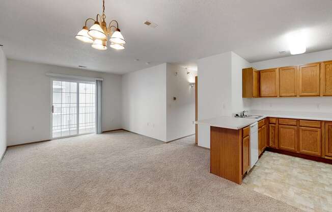 an empty living room and kitchen with wood cabinets