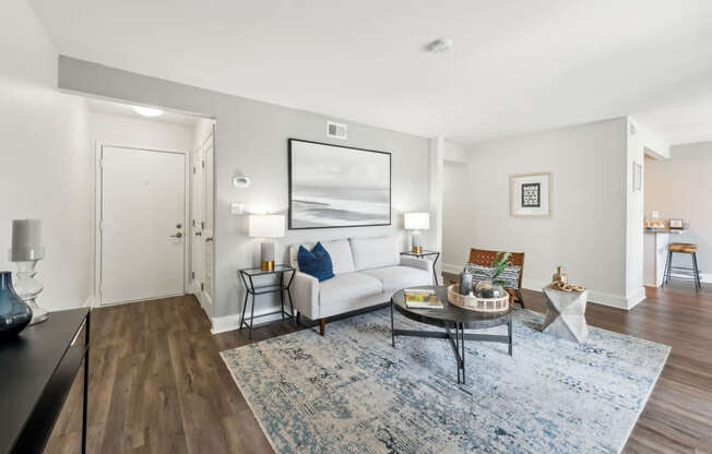 A living room with a white couch and a blue rug.