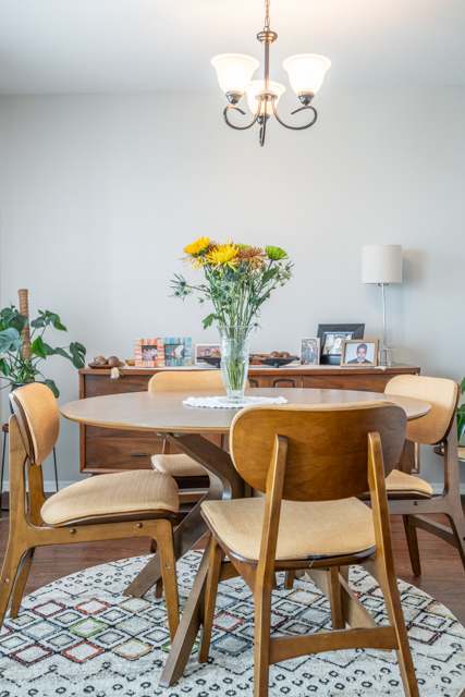 A dining room with a table, chairs, and a vase of flowers.