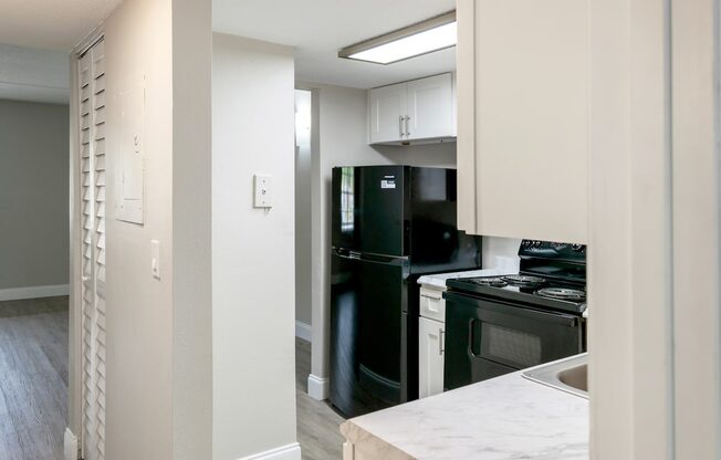 a kitchen with black appliances and white cabinets and a black refrigerator