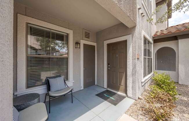 the front porch of a house with a chair and a door