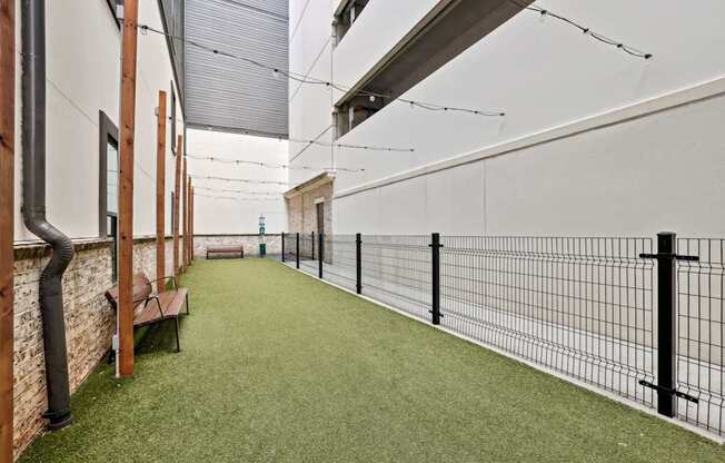 An enclosed dog park with benches, a trash can, and decorative lights at Alastair at Aria Village Apartments in Sandy Springs, GA