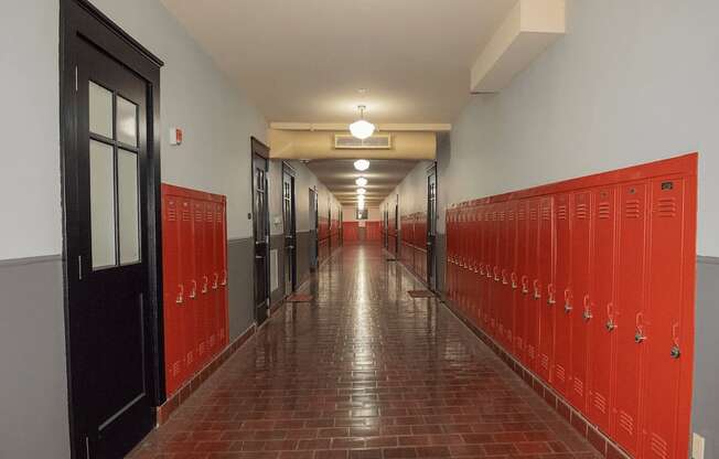 A long hallway with red lockers on the right and a black door on the left.