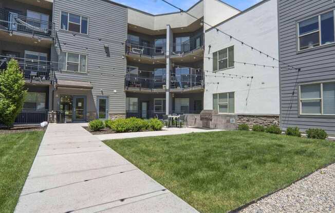 a view of the back of the building with a lawn and patio at The Flats at Riverwoods, Provo, UT