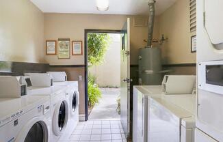 Pet-Friendly Apartments in Hayward CA - Glen Oaks - Laundry Room with Tiled Flooring, White Machines, and Tan Walls