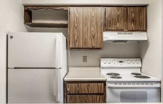 A white refrigerator and stove in a kitchen with wooden cabinets.