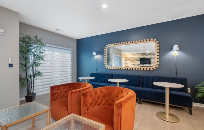 a living room with blue walls and orange chairs and a mirror