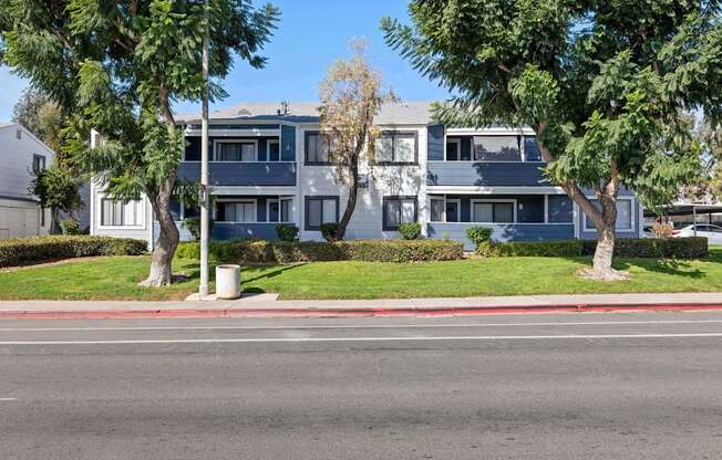 A street view of a residential area with apartment buildings and trees.