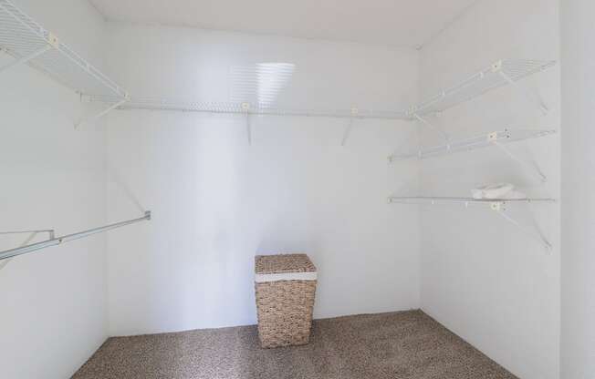 a walk in closet with white walls and a basket in the corner