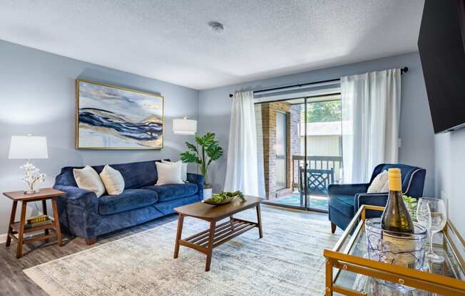 a living room with blue furniture and a sliding glass door to a balcony