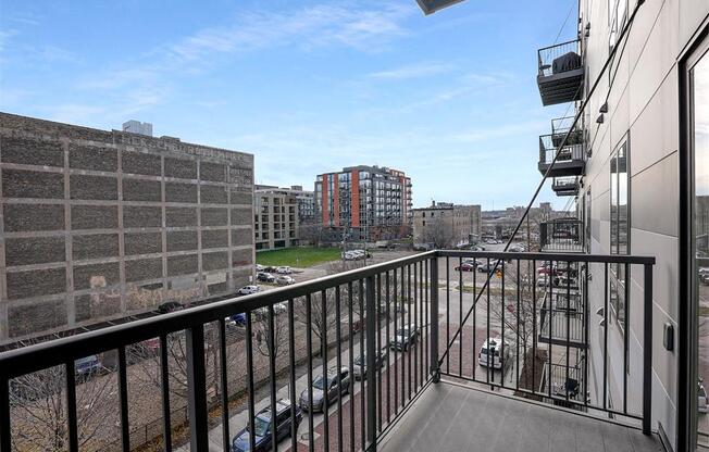 A balcony overlooks a city street with cars and buildings.