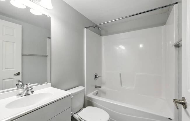 A white bathroom with a toilet, sink, and bathtub.