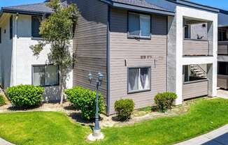 a gray and white building with a lamp post in the middle of a grassy areaat Lincoln Park Apartments, Corona, 92882