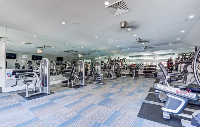 A gym with a variety of equipment including treadmills, weights, and exercise machines.